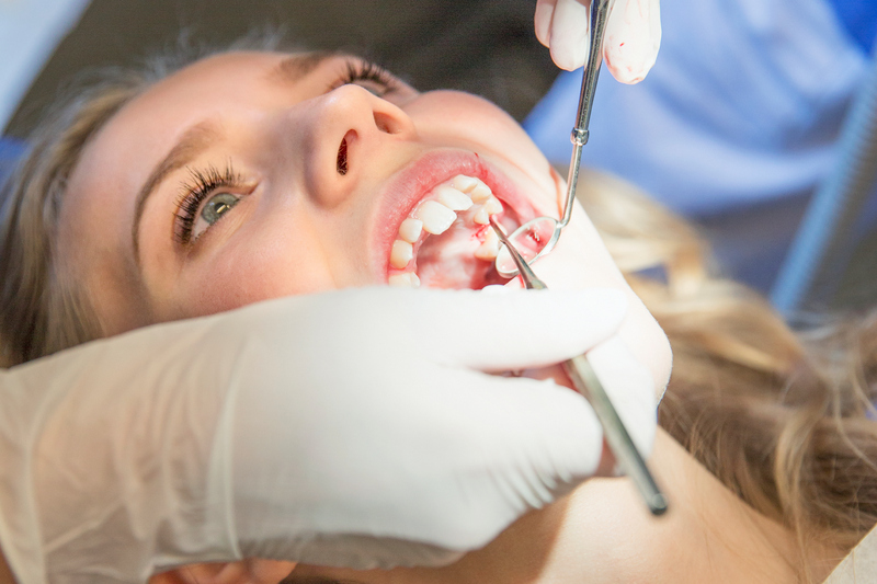 En person som ligger ner blir undersökt av en tandläkare.