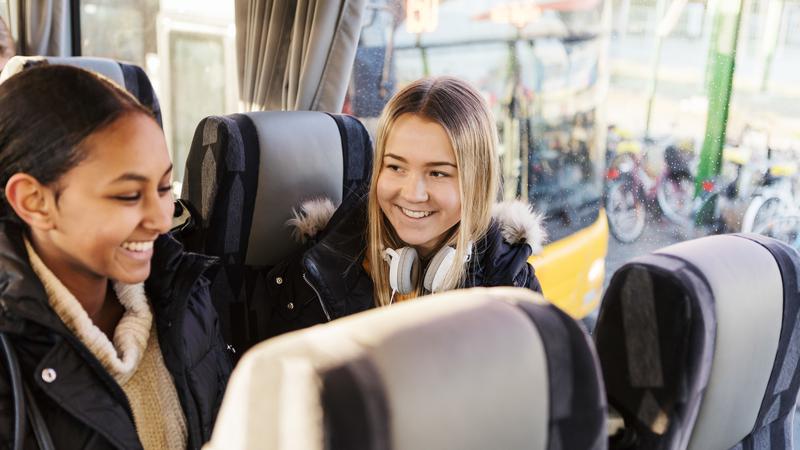 Två unga personer sitter bredvid varandra på en buss.