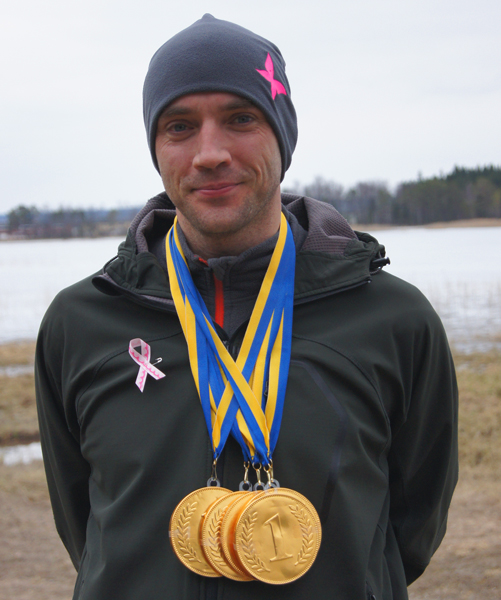 En löparklädd man med flera guldmedaljer runt sin hals