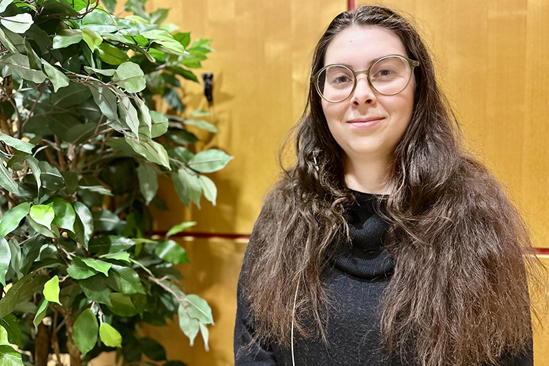 Leende person i brunt lockigt långt hår och glasögon