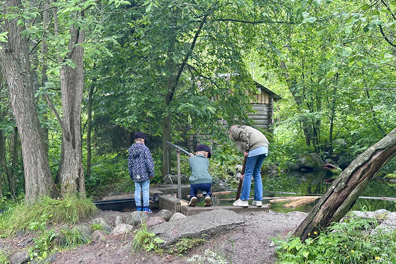 Tre barn upptagna av lek fotade bakifrån