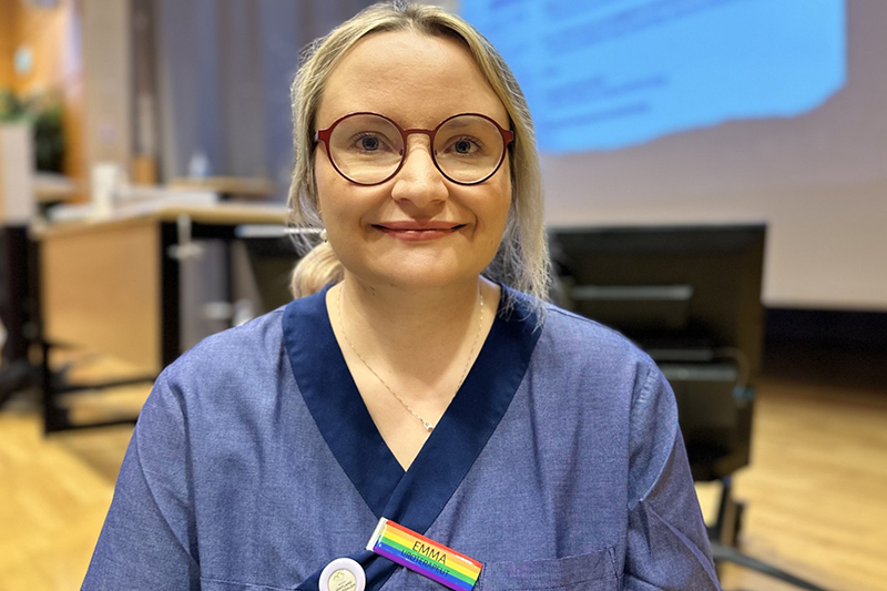 Person i vårdkläder ler mot kameran.
