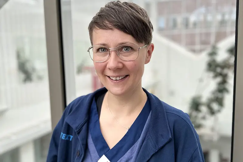 Vårdklädd person ler mot kameran.