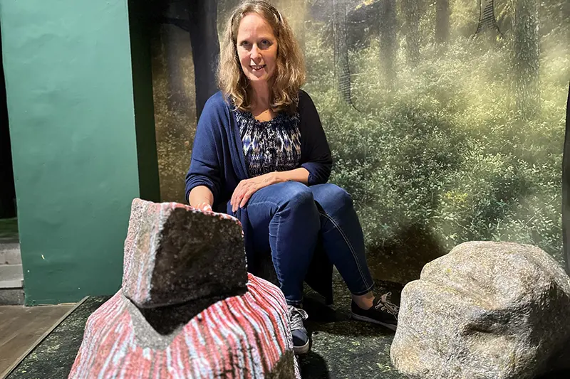 En person sitter bland stenar inomhus.