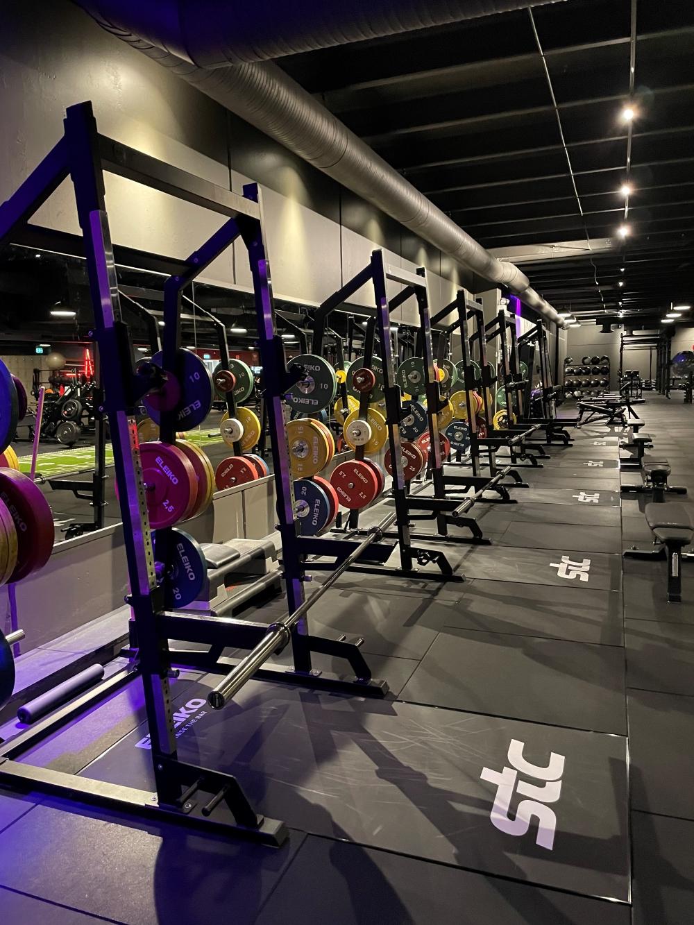 Öppen yta på gymmet med många skivstångsställningar.