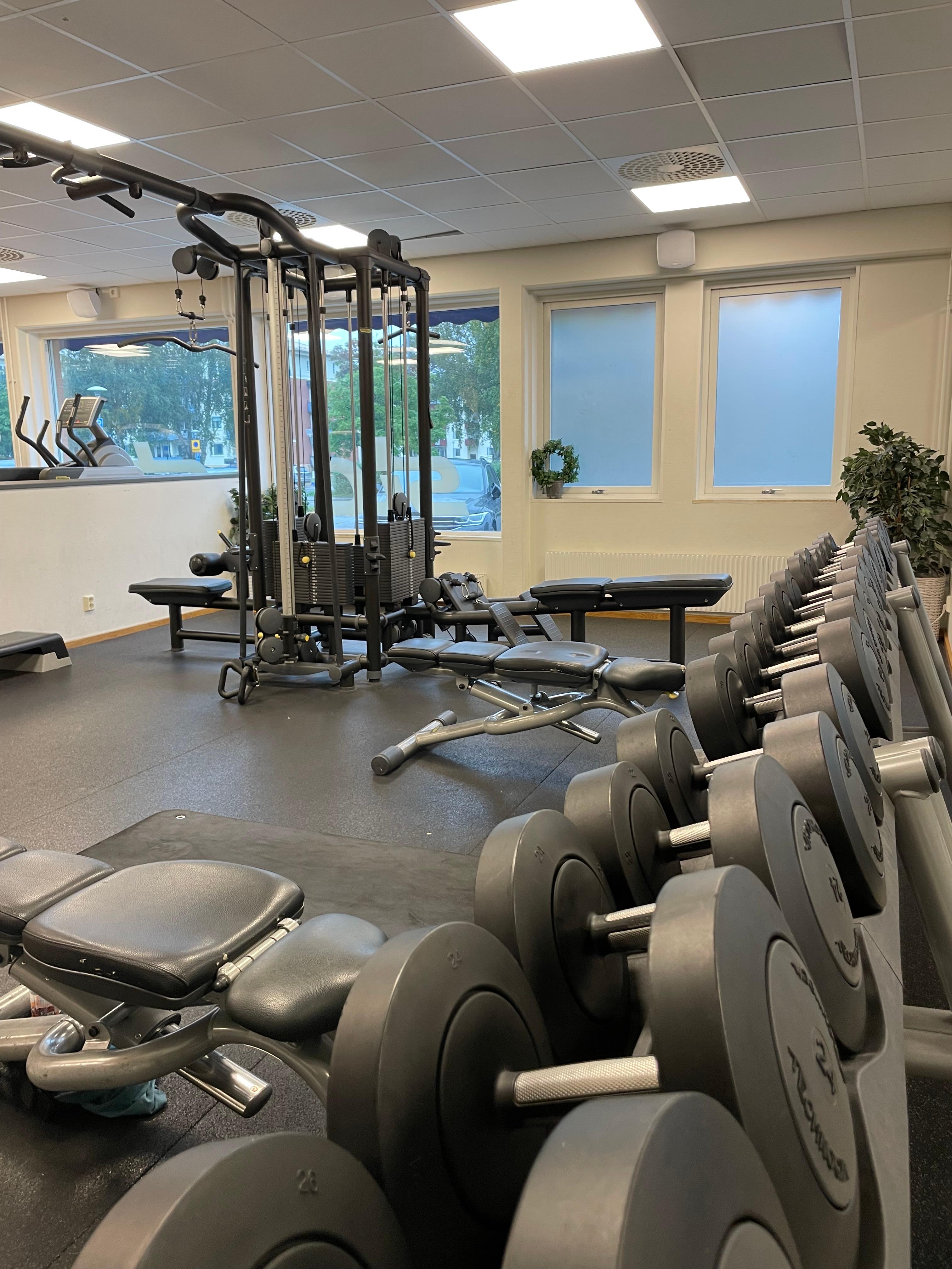 Gymdel med hantlar, en träningsbänk och en ställning att göra övningar i sittande eller stående syns även.