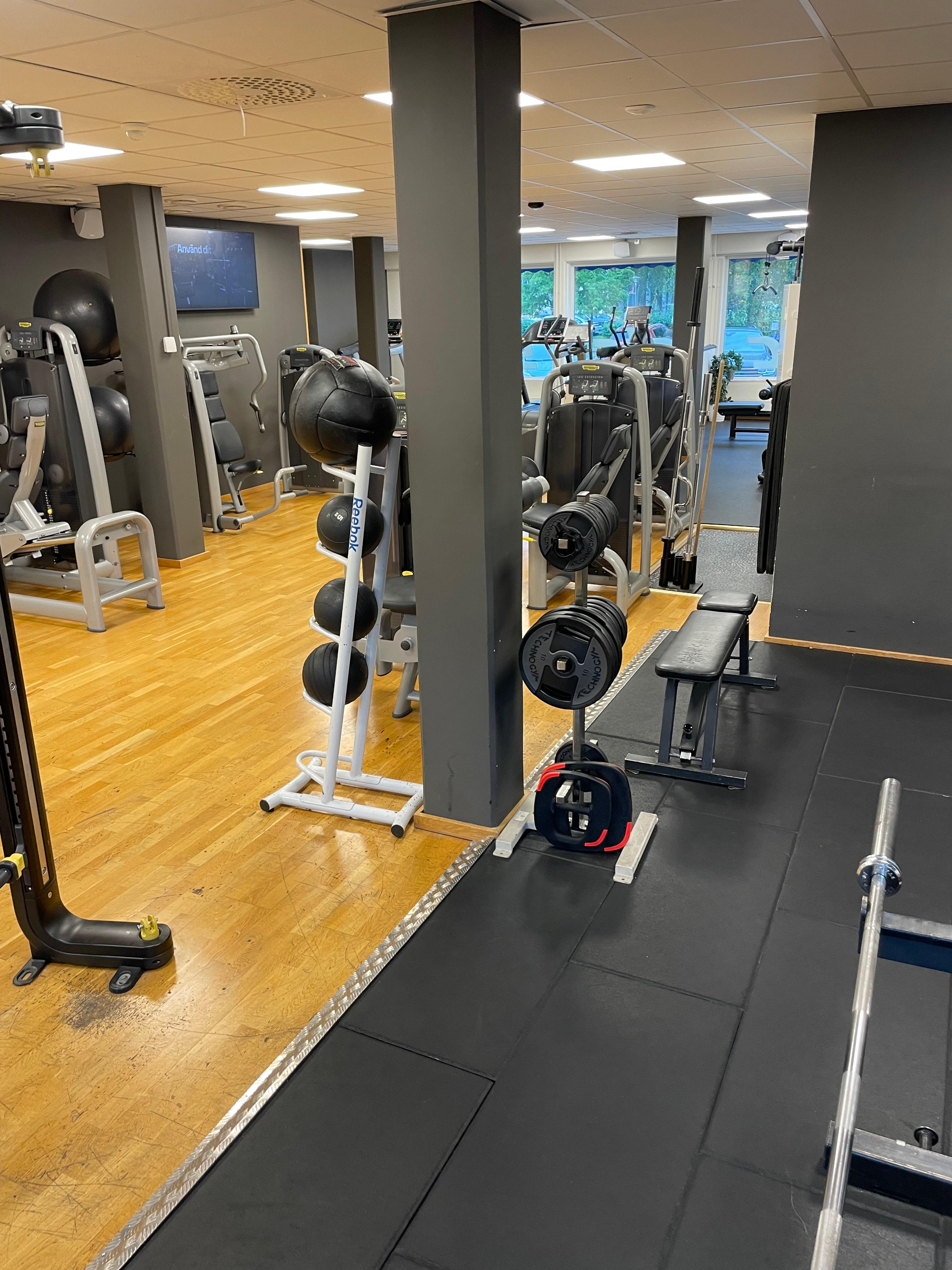 Gymdel där bollar i olika vikt syns, i bakgrunden även träningsmaskiner.