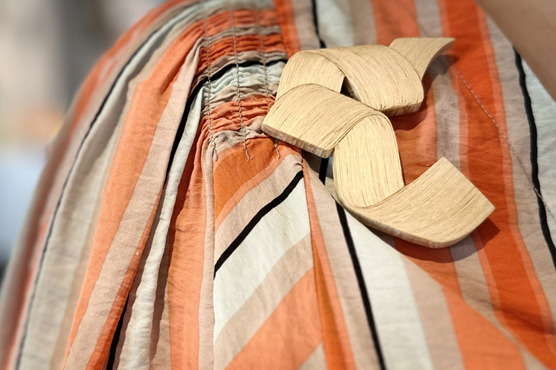 Närbild på en stor brosch på en randig blus