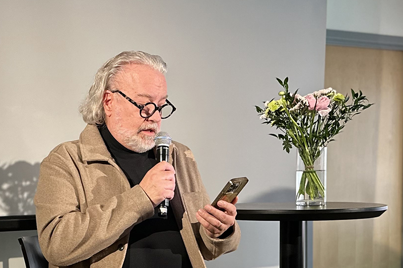 En person i kavaj och glasögon pratar i en mikrofon