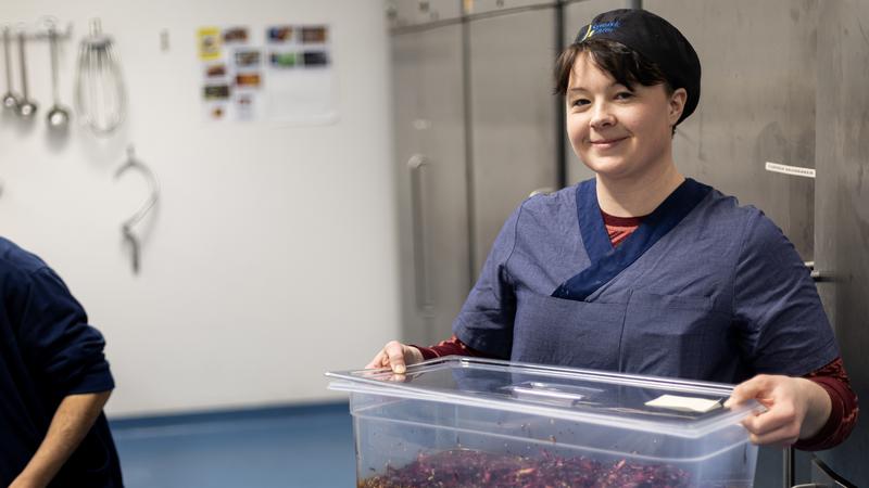 En kvinna håller i en behållare med sallad.