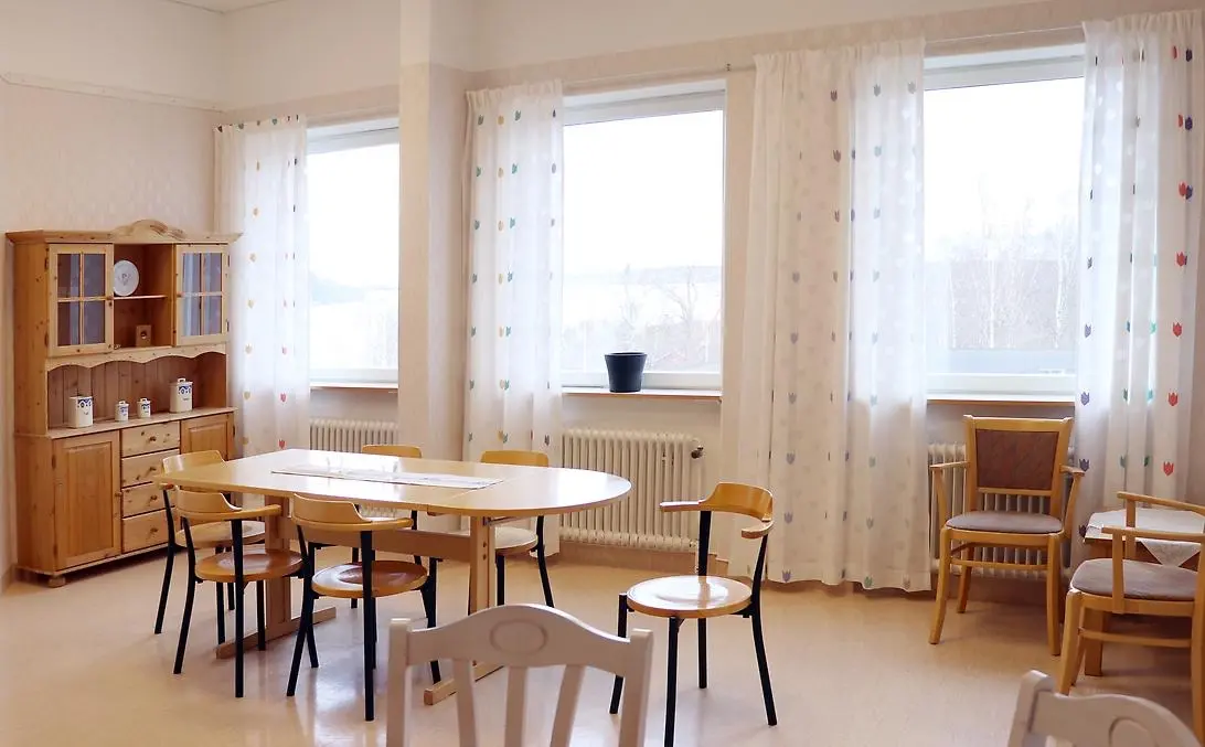 Köksmiljö inne på patienthotellet Eira, med stolar, bord, skåp och stora fönster med gardiner.