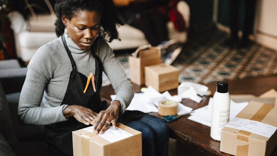 Illustrativ bild; n kvinna pakar ett paket med varor som ska skickas iväg. 