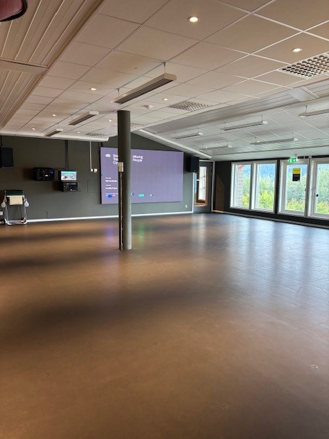 Stor, öppen gruppträningssal, stora fönster på långsidan, en stor skärm finns längst fram i salen.