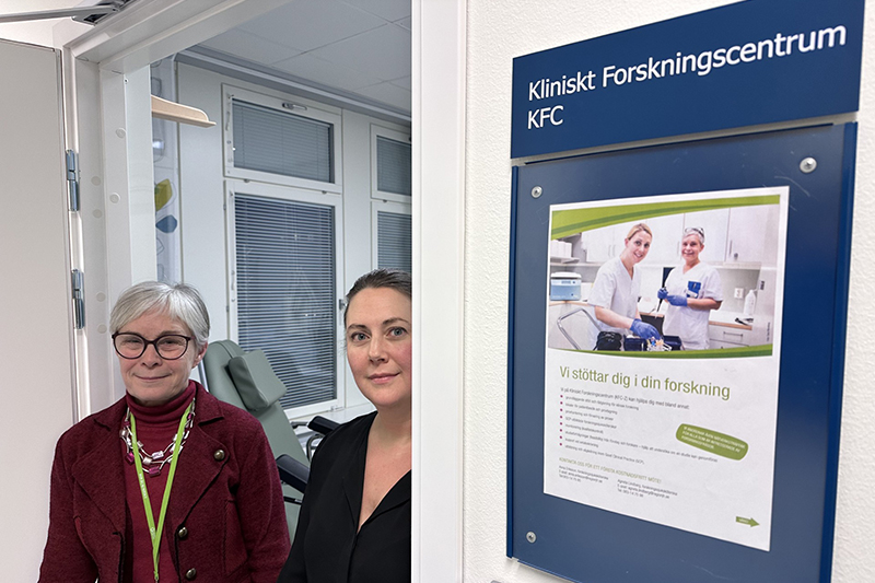 Två personer kikar fram ur en dörröppning och ser glada ut