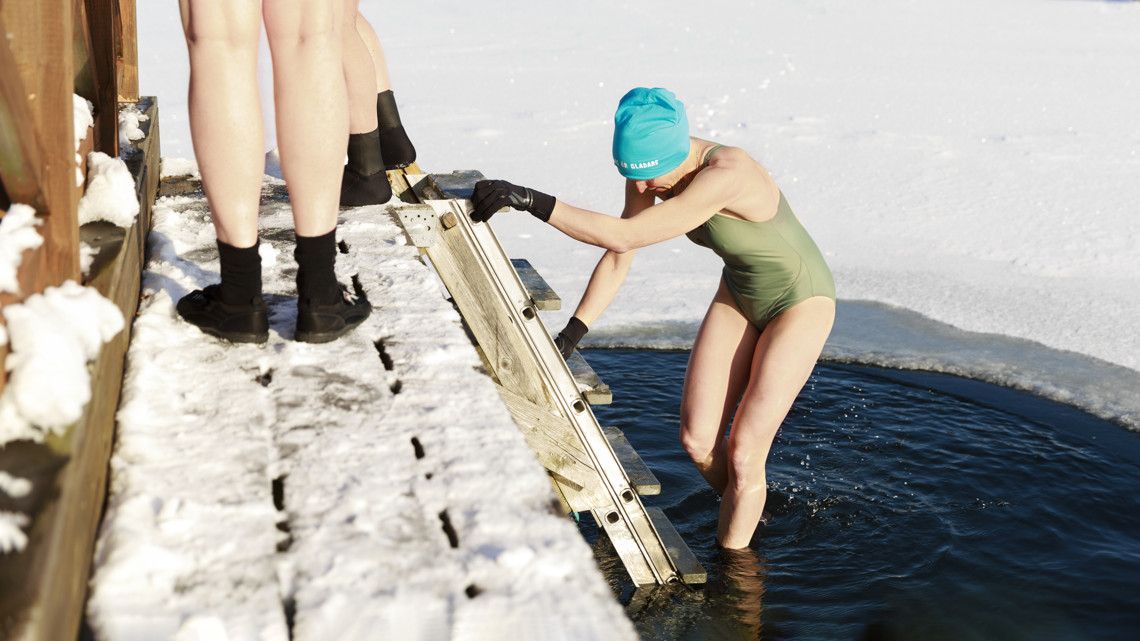 Två skolungdomar pratar och ler sittandes på en buss.