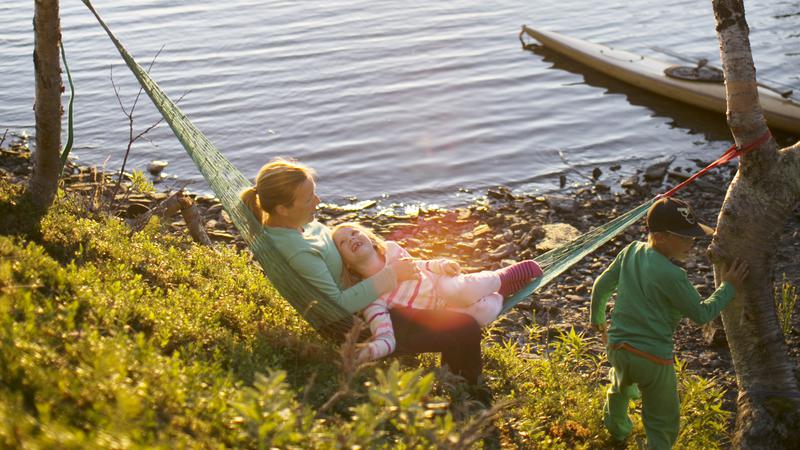 Personer i hängmatta vid fjällsjö.