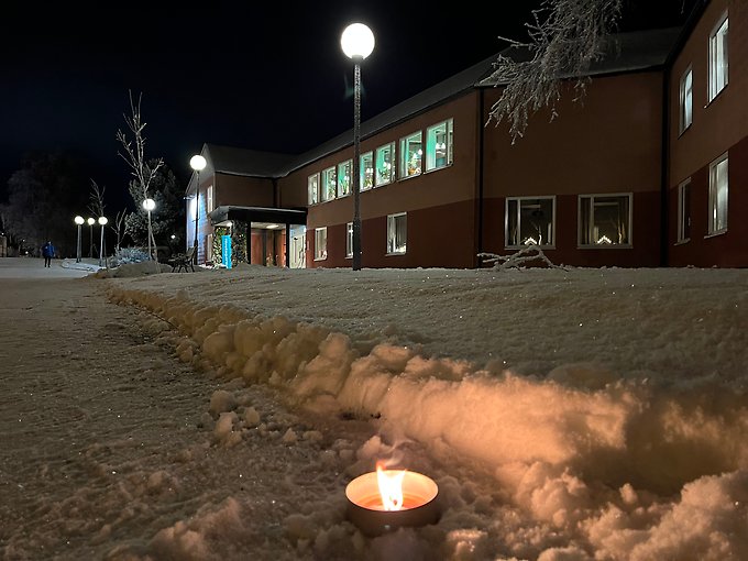 Ranågårdens tegelbyggnad upplyst i natten. På den snöiga marken utanför syns en tänd marschall.