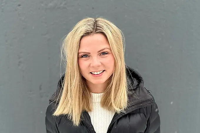 En leende person tittar in i kameran. 