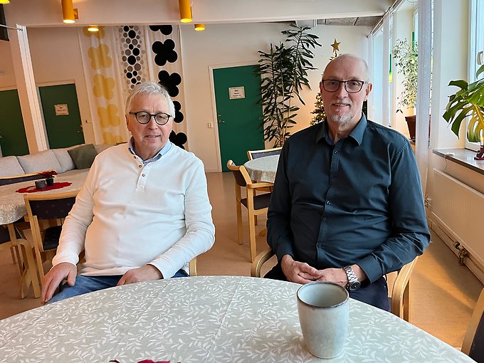 Ranågårdens ägare Asle Sundal och verksamhetschef Anders Haglund sitter vid ett köksbord med en kaffekopp framför sig i en julpyntad samlingslokal.