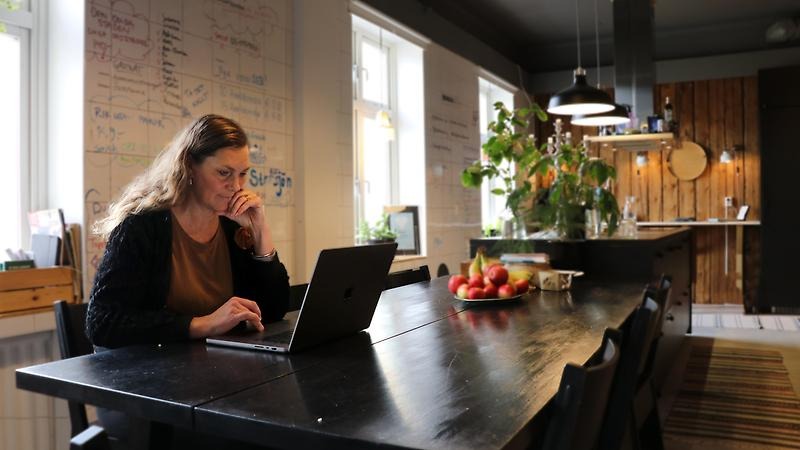 Företagaren Sara Carlemår sitter vid sin bärbara dator vid ett köksbord på kontoret.