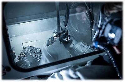 En arbetare i en skyddsdräkt putsar metallbit