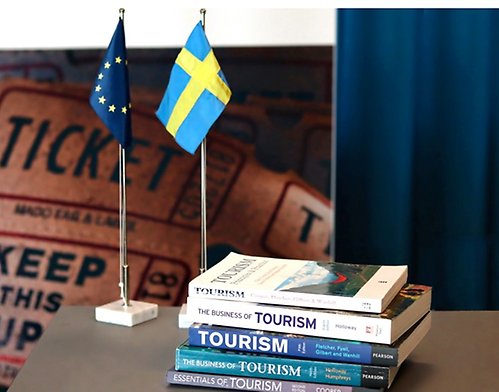 Bild på en bunt böcker om turism samt en EU-flagga och Sveriges flagga