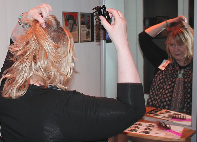 En kvinna sätter fast en hårklämma i sitt hår framför en spegel