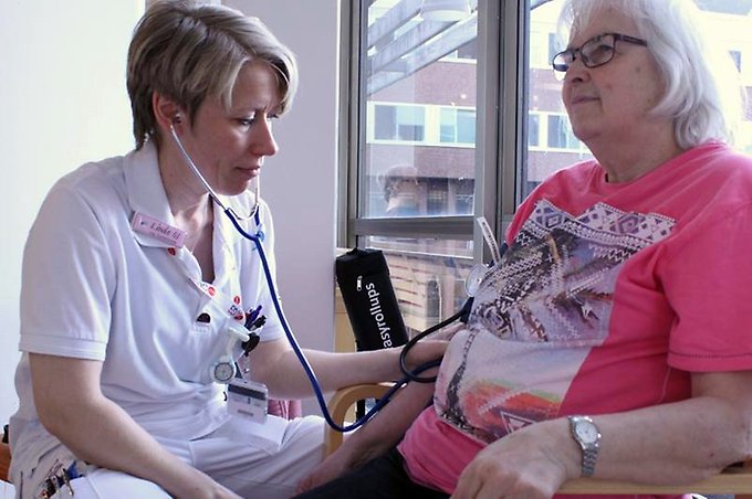 en sjuksköterska tar blodtrycket på en äldre dam