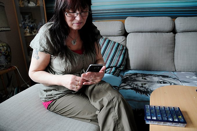 en kvinna sitter på en soffa och tittar på en mobiltelefon