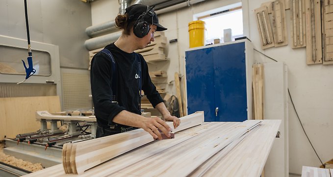 En anställd på Åre skidfabrik jobbar vid ett arbetsbord med utskurna träplankor som ska bli till skidor. Foto: Tobias Liljeroth