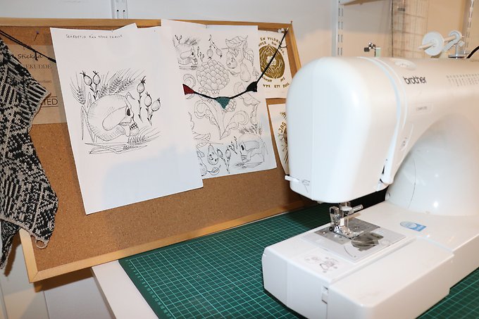 Designskisser upphängda på en anslagstavla bakom en symaskin hos företaget Beknitted. Foto: Region Jämtland Härjedalen