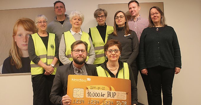 Gruppbild på personal från BUP tillsammans med medlemmar i Lions club Brunkullan. Främst i bild hålls en gåvocheck på 10 000 kronor upp