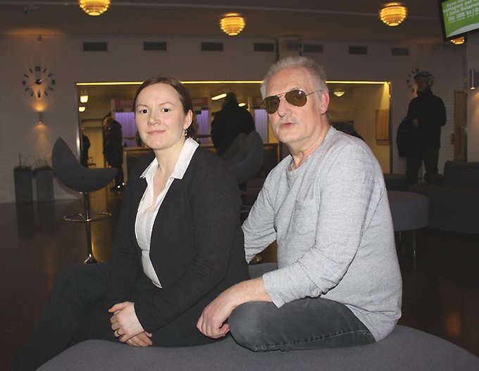 En kvinna och en man sitter tätt ihop på en stor puff