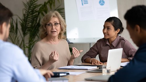 Möte mellan fyra personer, med en presentation på skärm bakom dem vid konferensbordet.