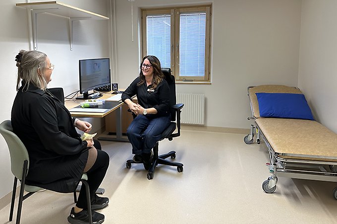 Två personer sitter mittemot varandra i ett mottagningsrum i samtal