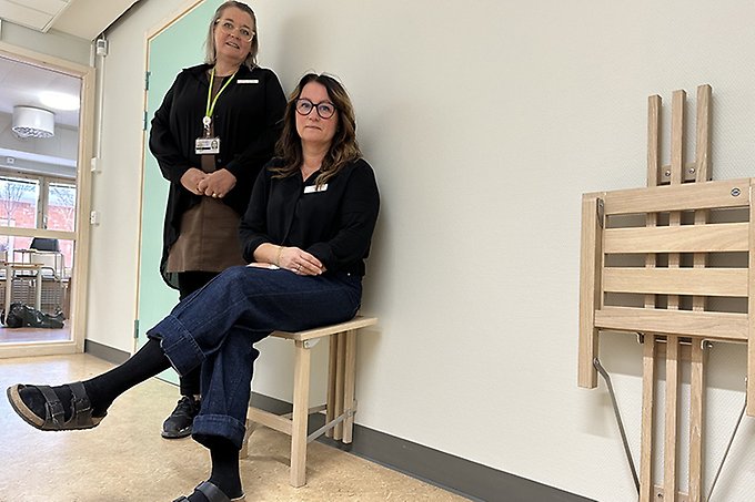 Två personer i en korridor. En sitter och en står.