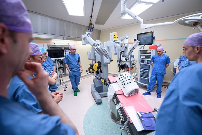 sjukvårdspersonal i operationskläder står runt en operationsrobot