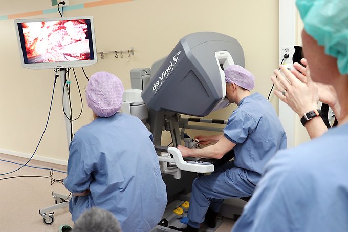 Urologen Andreas Lundgren sitter vid spakarna i modulen och styr robotens armar med instrumenten inne i patientens buk. Under den här operationen har han hjälp av en instruktör som sitter intill.