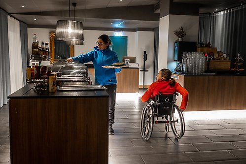 Två kvinnor vid frukostbudffé varav en i rullstol