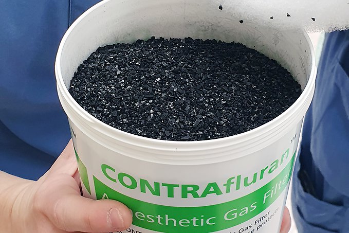 en plastburk med små svarta bitar av aktivt kol i