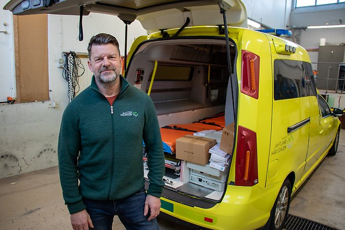 En person står bakom en ambulans med öppen baklucka, inne i ett garage.