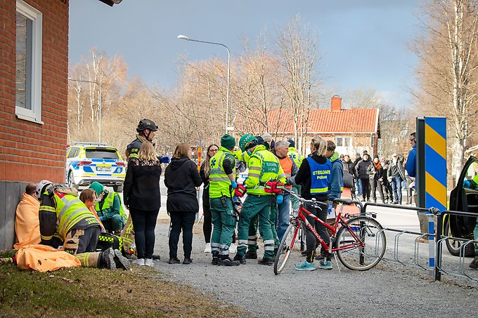 ambulanspersonal och räddningstjänst utanför en skola tillsammans med figuranter som spelar chockade och skadade