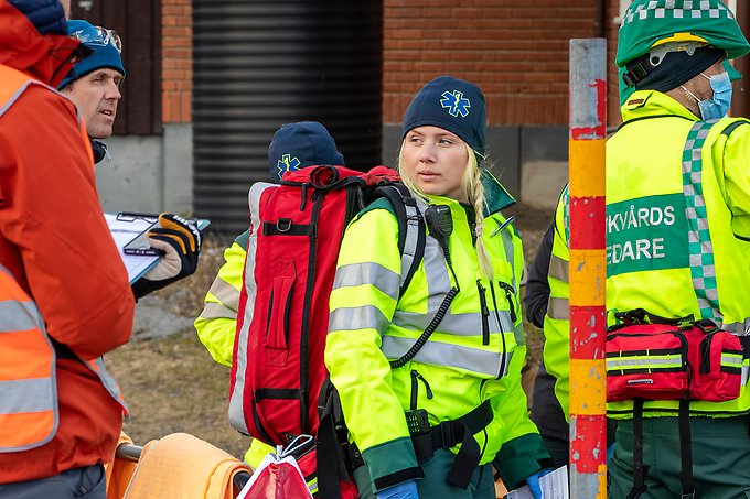 en ambulanssjukvårdare med mössa och en stor röd ryggsäck