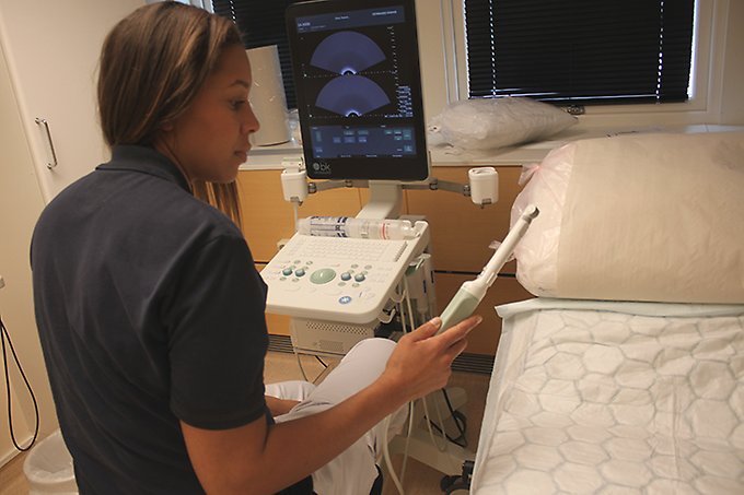 En sjuksköterska sitter vid en tv-skärm och håller i en ultraljudsstav