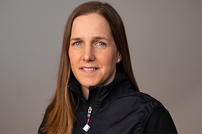 Foto på leende person i mörk tröja med blå ögon och mörkt långt hår