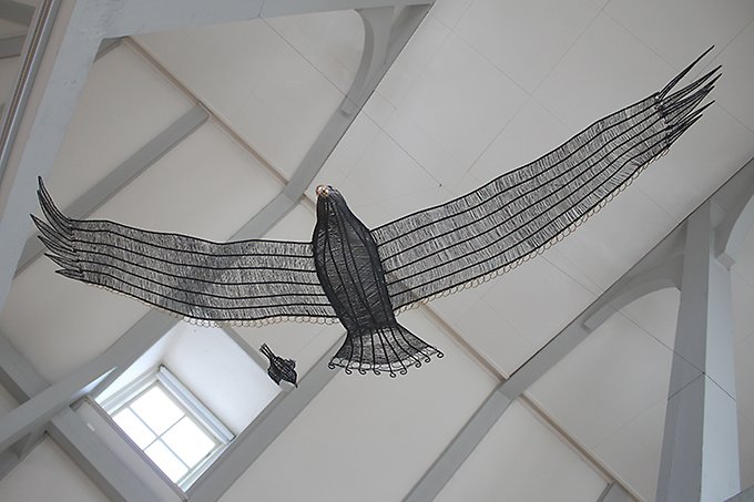 En gigantisk fågel gjord i järntråd svävar fritt under taknockarna i Ahlbergshallen