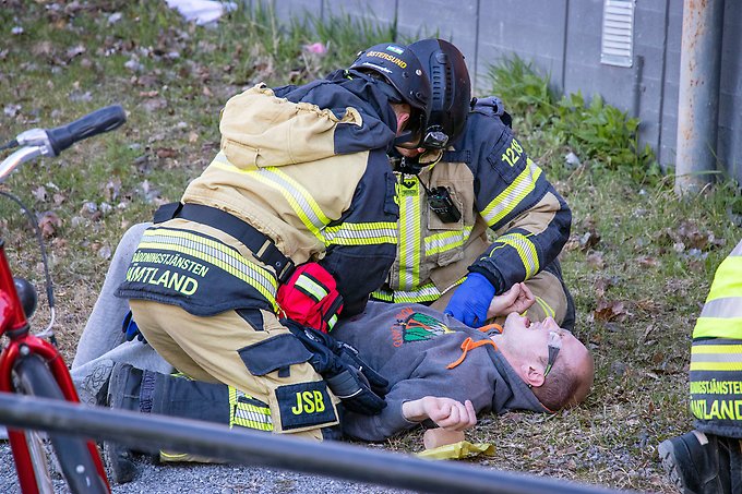 två personer från räddningstjänsten tar hand om en person som ligger på marken och låtsas vara skadad