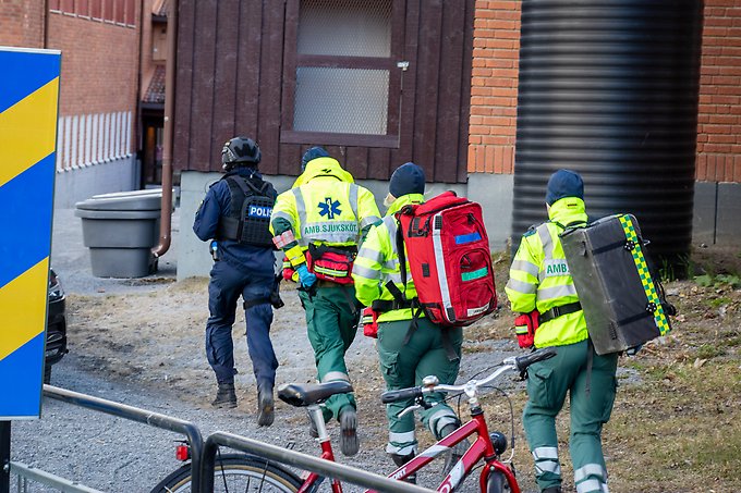 tre ambulanspersonal joggar efter en insatspolis utanför en skola
