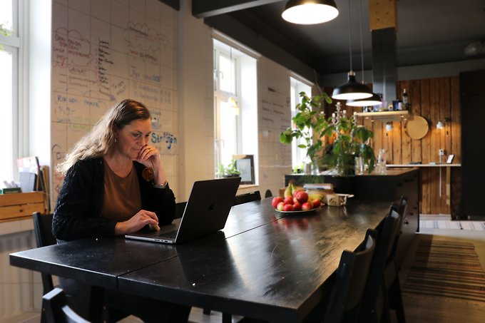 Företagaren Sara Carlemår sitter vid sin laptop, vid ett mörkt träbord. 
