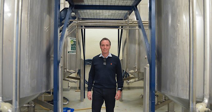 Porträttbild på företagaren Anders Åkerström, i fabriksmiljö med ståltunnor bakom. Foto: Malin Palmqvist